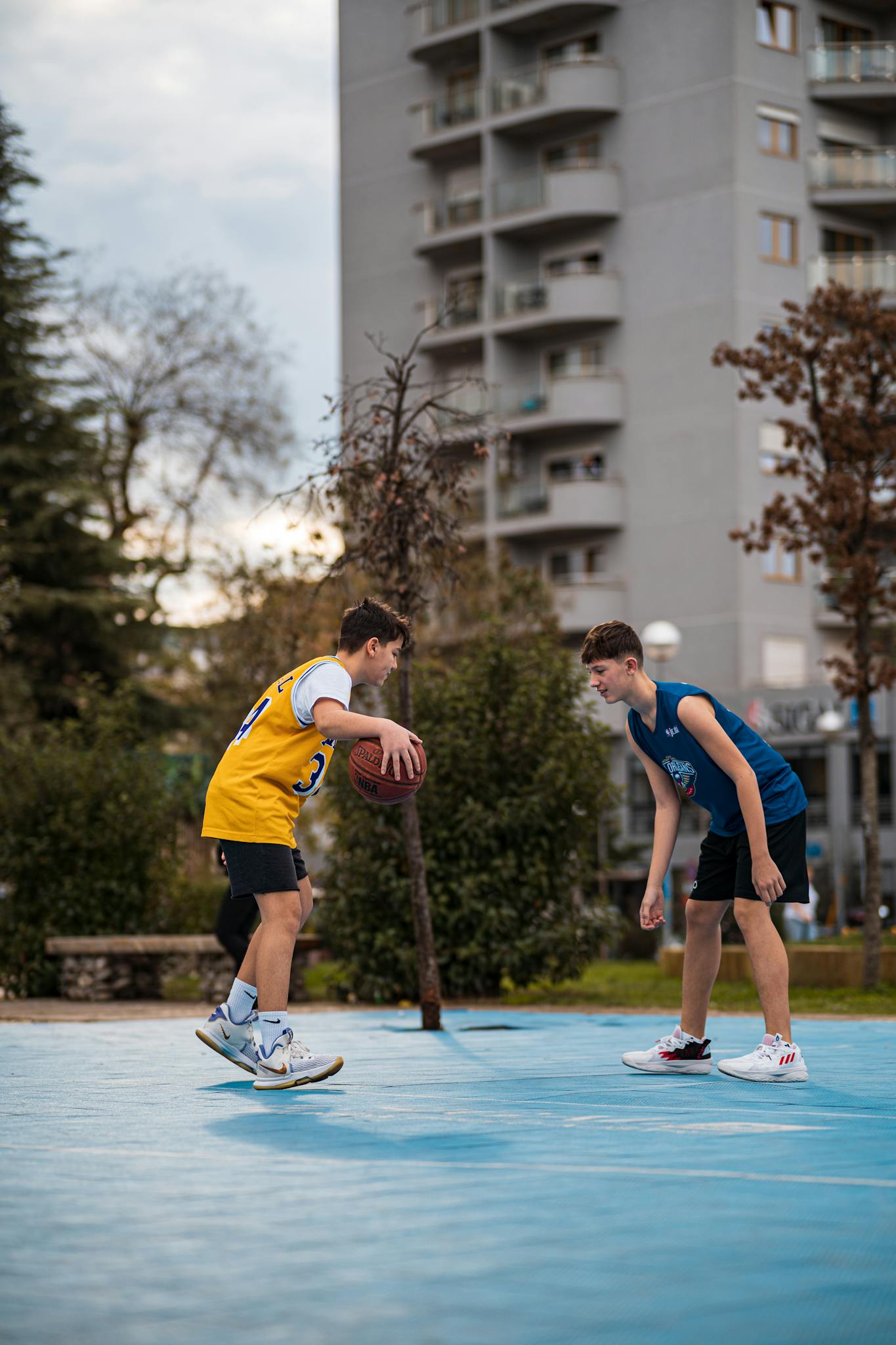 Energetic teenagers enjoying a basketball game in an outdoor urban court.
